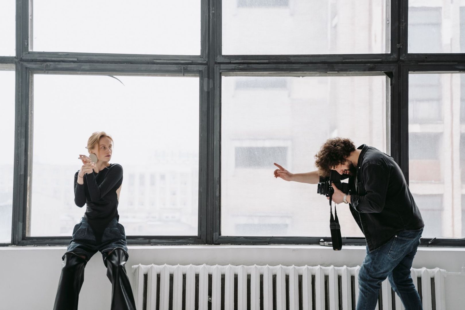 Fotograf fotograferar en modell i naturligt ljus från stora fönster
