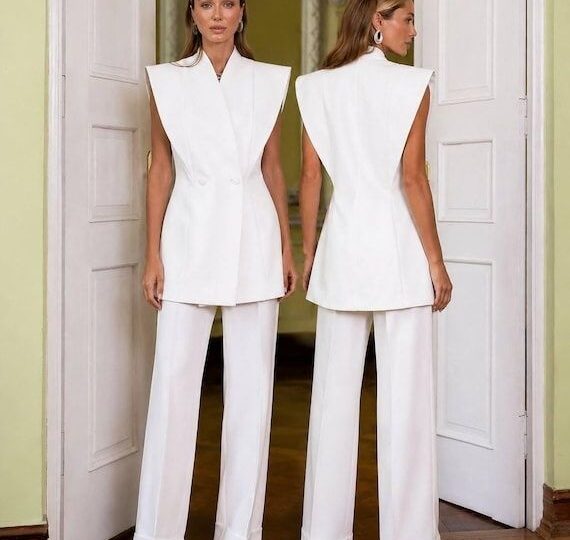 Två kvinnor i vita, skräddade outfits med markerad silhuett