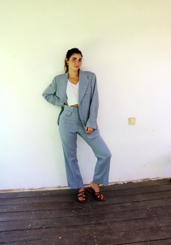 Person i ljusgrå blazer och högmidjade byxor med lång silhuett
